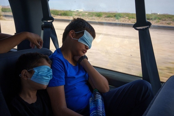 Migrant children sleep on their way to the El Paso International Airport. (Photo by PAUL RATJE/AFP via Getty Images)