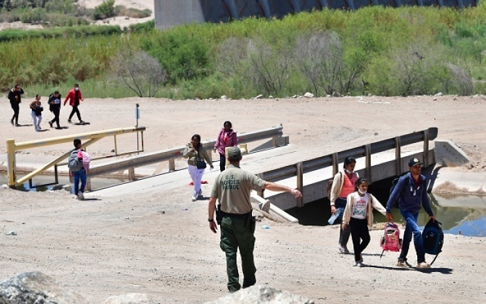 A US Border Patrol officer directs migrants arriving at the US-Mexico border near Yuma, Arizona, on May 16, 2022. (Photo by FREDERIC J. BROWN/AFP via Getty Images)