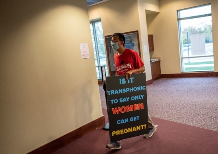A man carries a sign into a Loudoun County Public Schools (LCPS) board meeting in Ashburn, Virginia on October 12, 2021. (Photo by ANDREW CABALLERO-REYNOLDS/AFP via Getty Images)